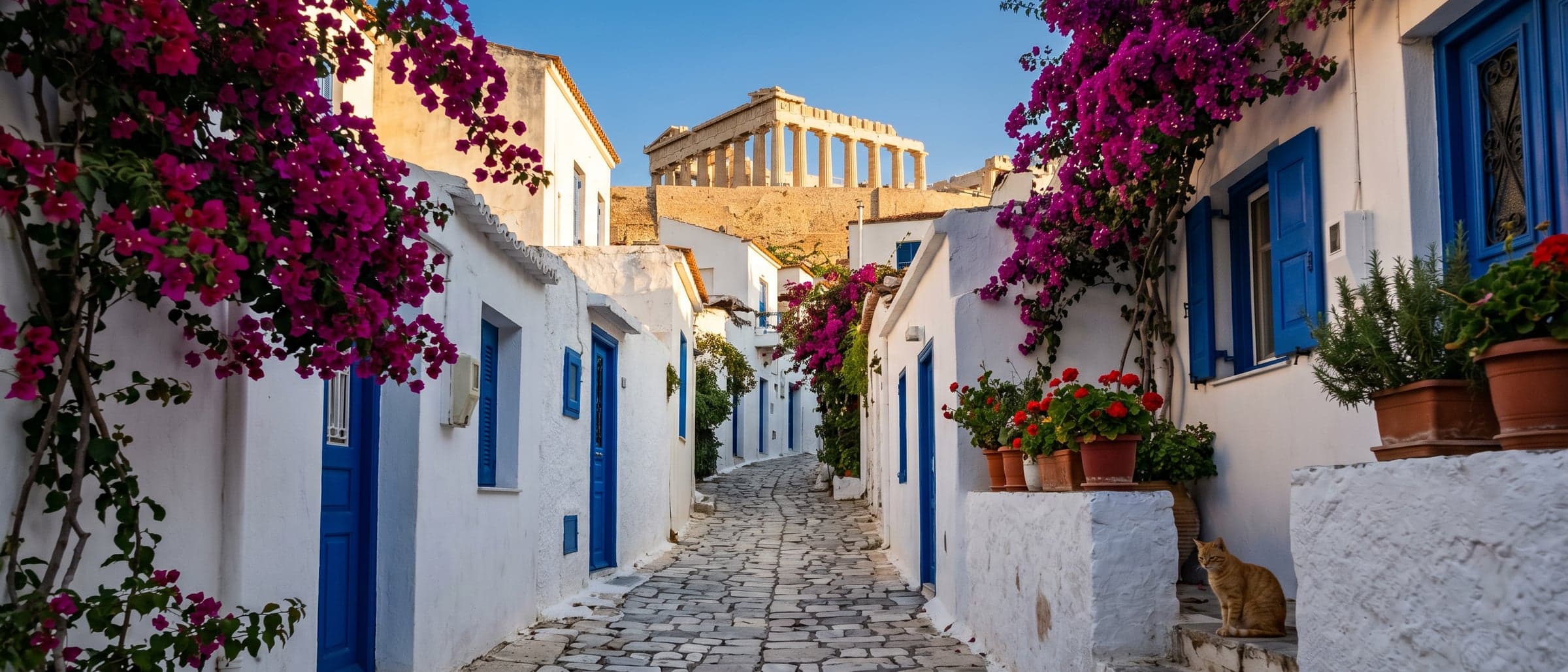 A narrow cobblestone alley in the Anafiotika neighbourhood — whitewashed Cycladic-style houses with blue doors, magenta bougainvillea, and the Parthenon framed at the top of the rise.