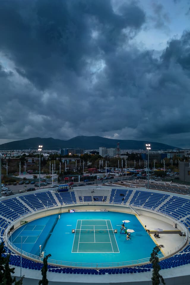 OAKA Centre Court interior after the 2025 refurbishment — blue seating, blue GreenSet court, empty bowl.